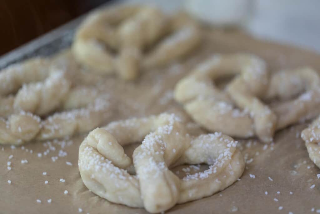 sourdough pretzel dough boiled and topped with egg wash and coarse salt on parchment paper