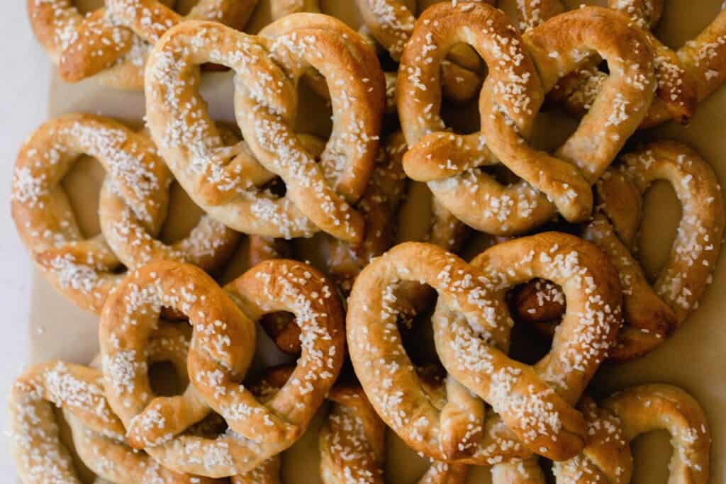sourdough discard pretzels covered in pretzel salt stack on a parchment lined tray