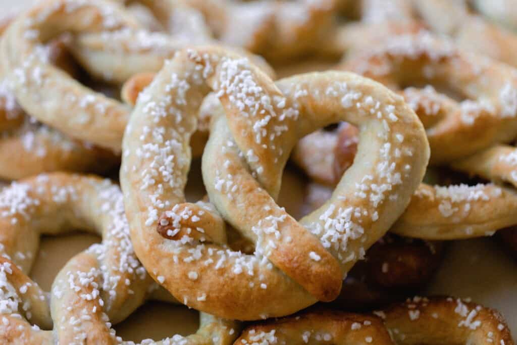 sourdough discard pretzels covered with course salt laying on a bed of pretzels