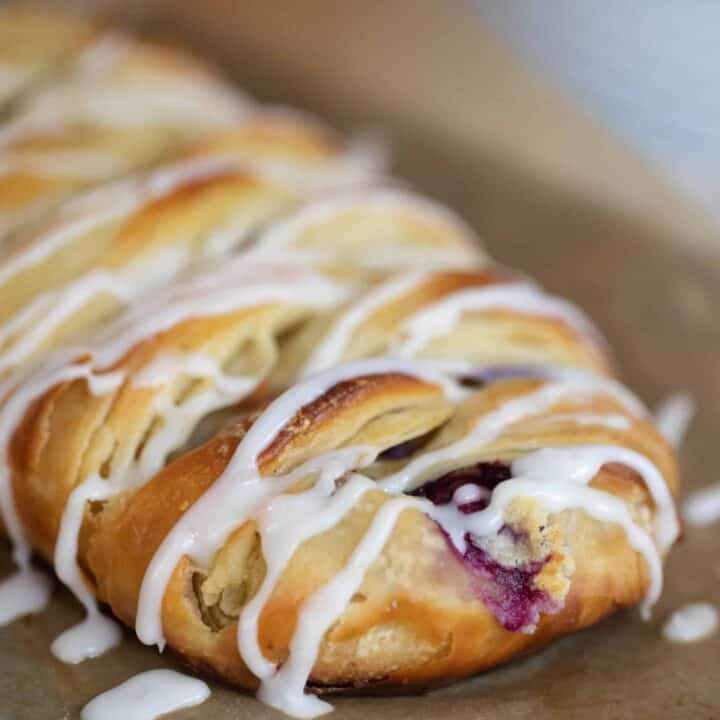 sourdough pastry braid drizzled with icing on parchment paper