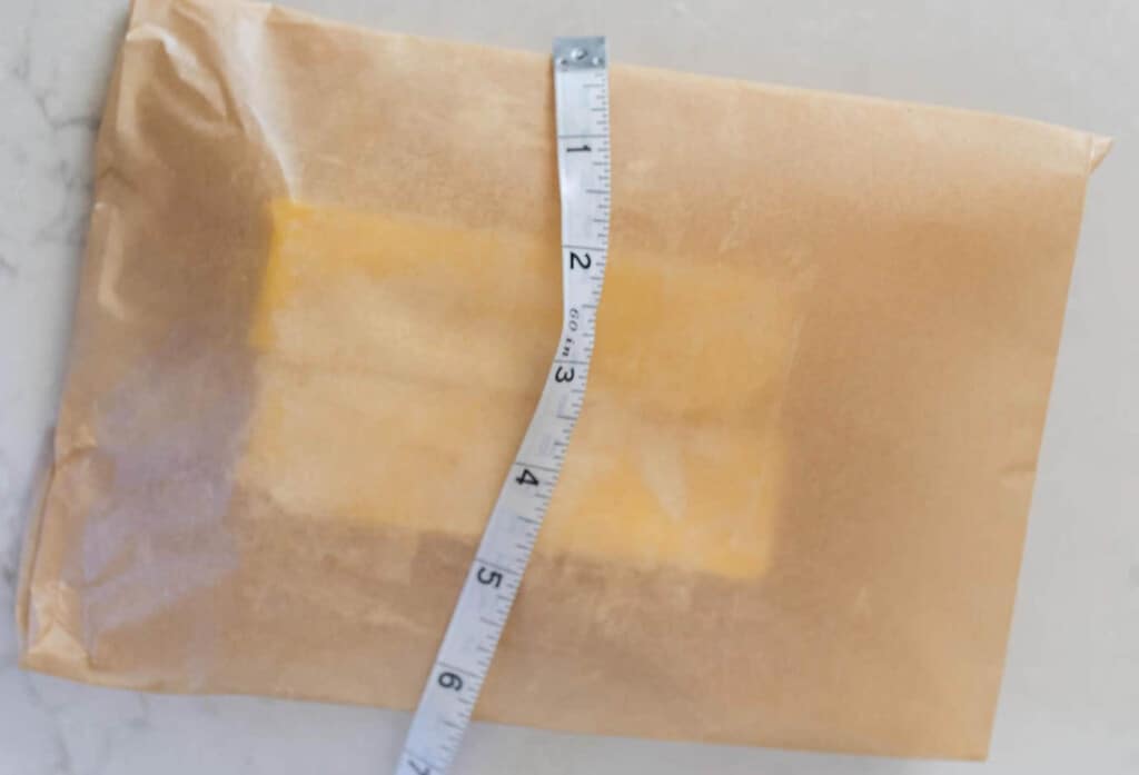 butter wrapped in parchment paper with a tape measure over it