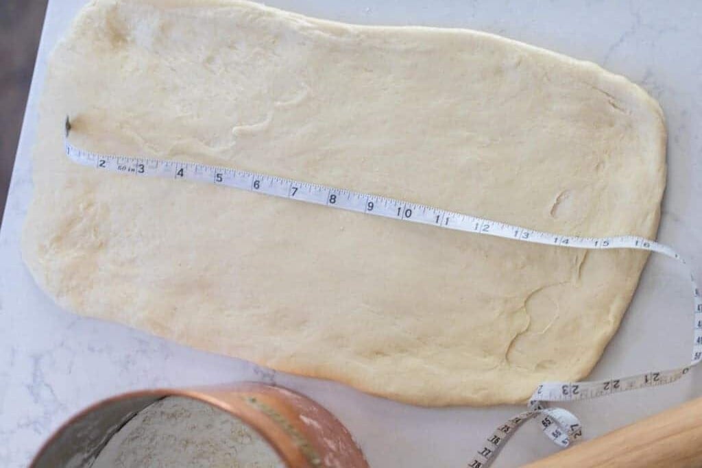 dough rolled out into a rectangle with a measuring tape down the center