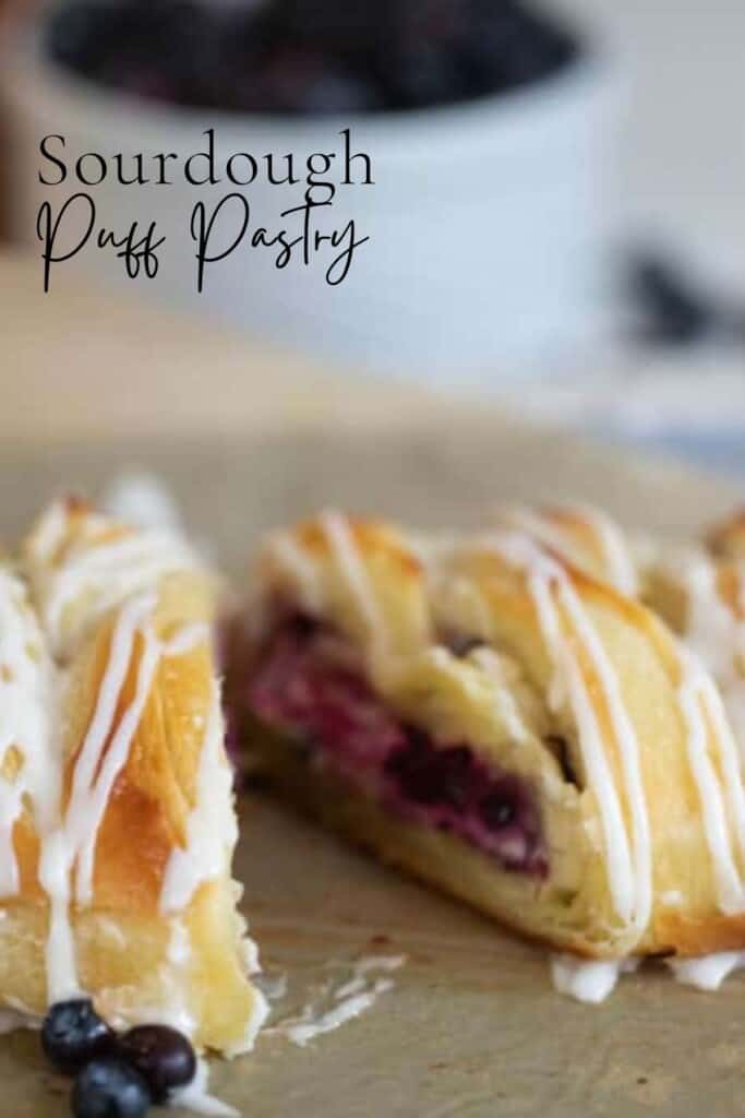 sourdough puff pastry with blueberry cream cheese filling sliced in half on parchment paper