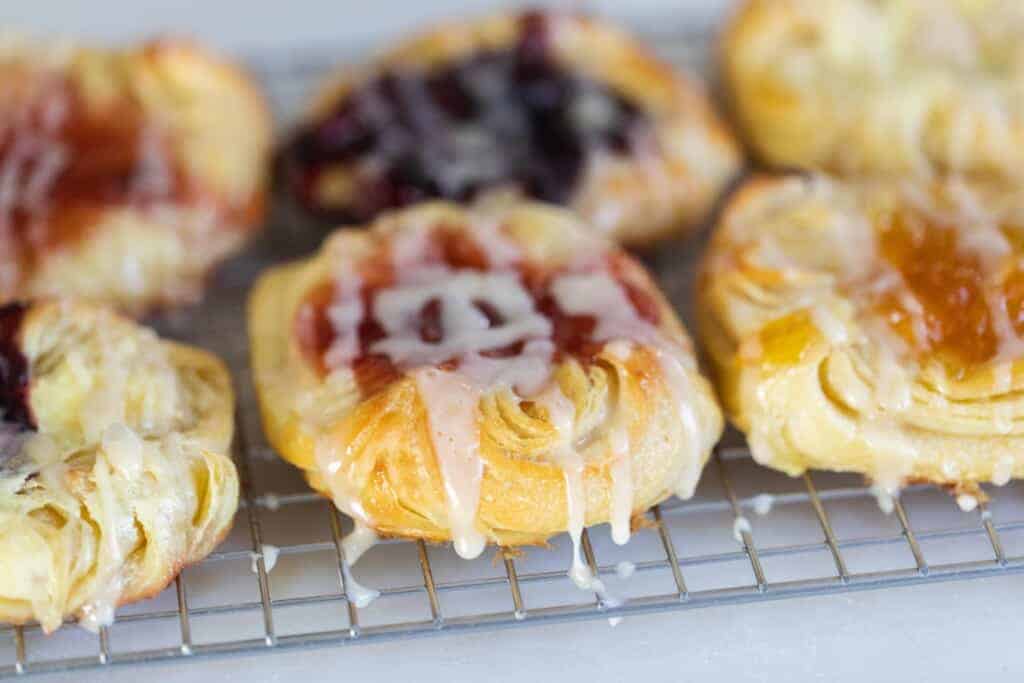sourdough puff pastries with fillings and topped with sweet glaze on a wire rack