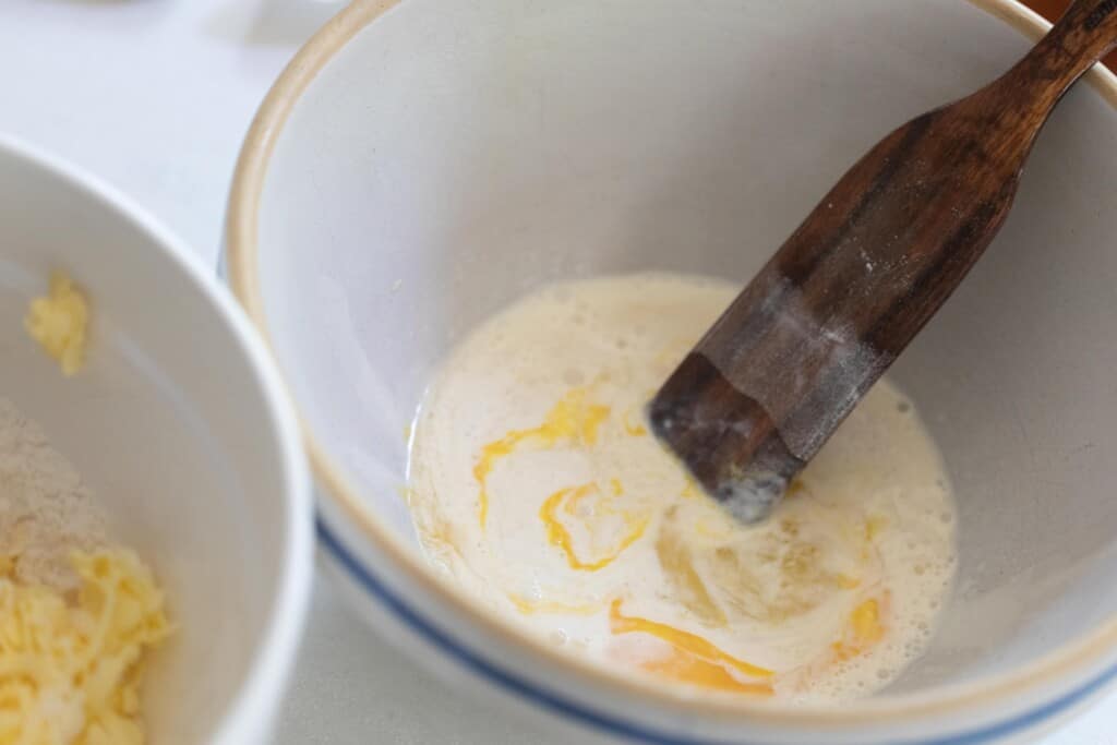 mixing wet ingredients in a ironstone bowl with a wooden spatula