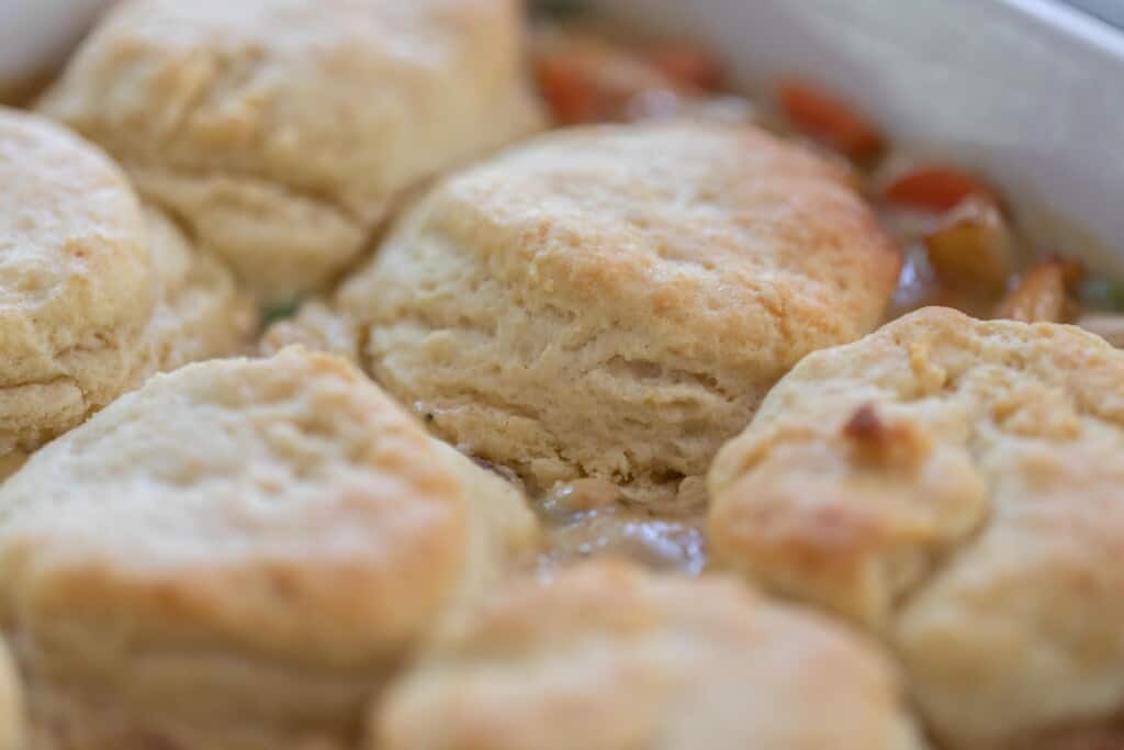 up close picture of sourdough biscuits on top of chicken pot pie filling.