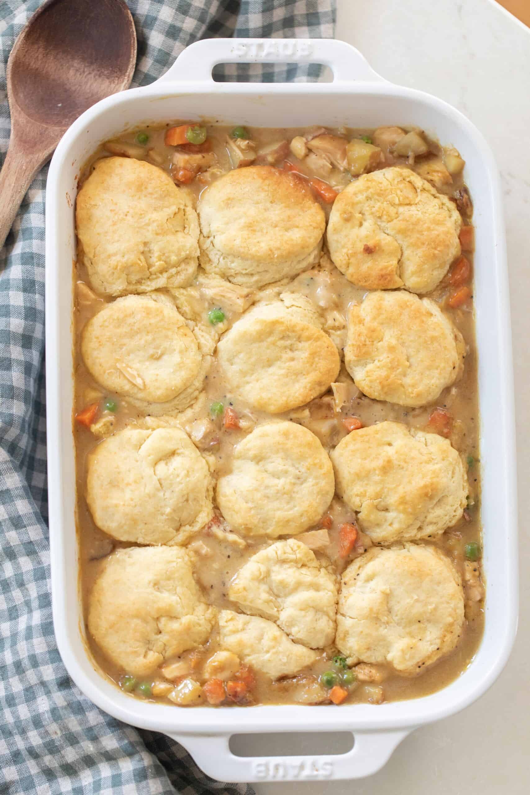 overhead photo of sourdough chicken pot pie in a white baking dish on a blue and white checked towel