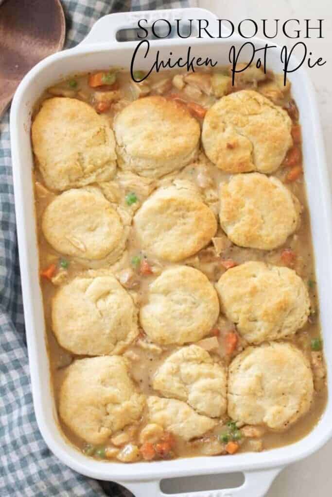 overhead photo of chicken pot pie topped with sourdough biscuits in a white baking dish on a white and blue checked towel