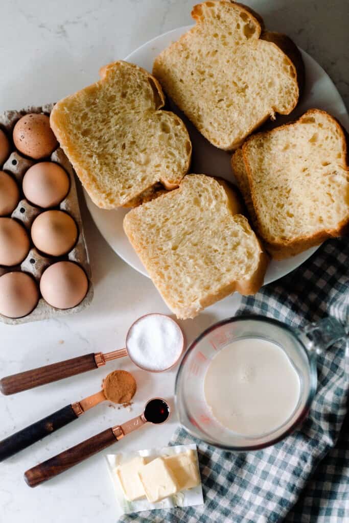 slices of brioche, eggs, milk, and spices on a white countertop