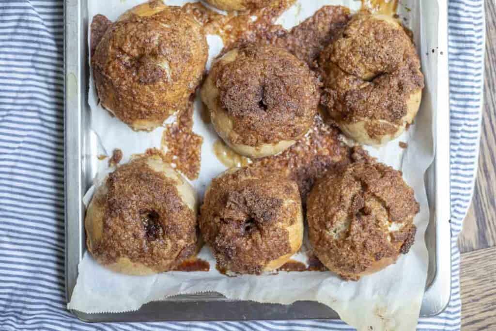 overhead photo of six sourdough cinnamon crunch bagels on a parchment lined baking sheet