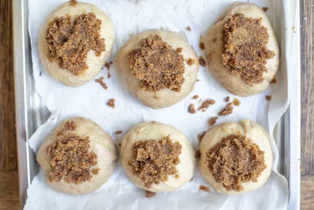 unbaked bagels with cinnamon sugar topped on each bagel on a parchment lined baking sheet