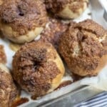 four sourdough cinnamon crunch bagels on a parchment lined backing sheet on a blue stripped towel