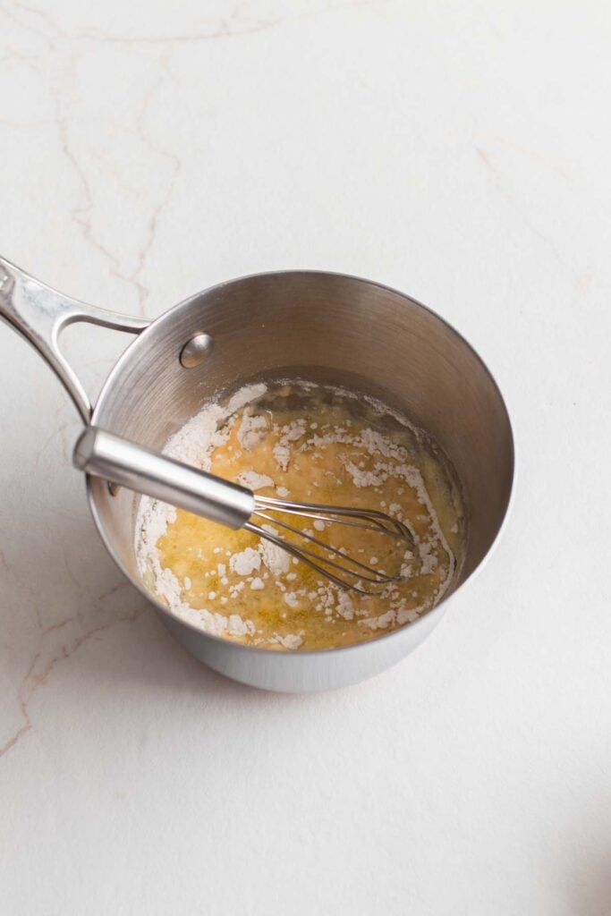 A small pot with butter and flour and a whisk.