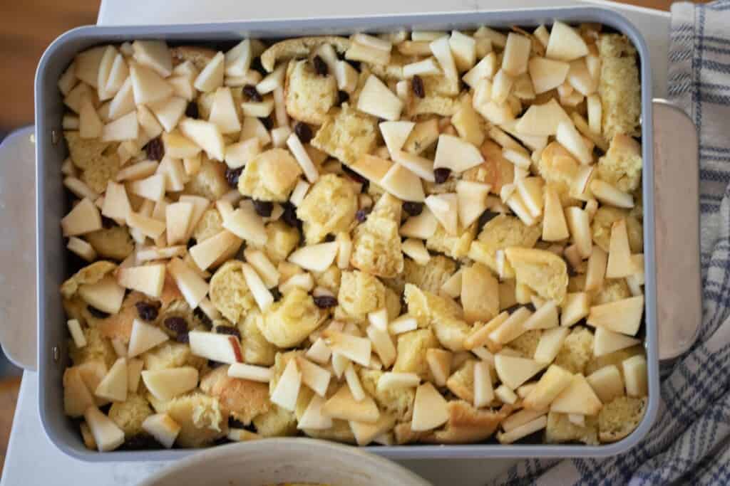 bread diced in a baking dish with chopped apples and raisins