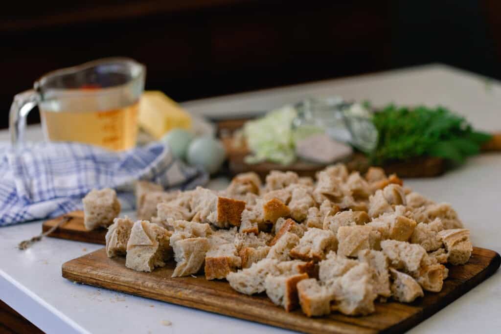 sourdough bread cut in cubes on a wood cutting board on a white countertop