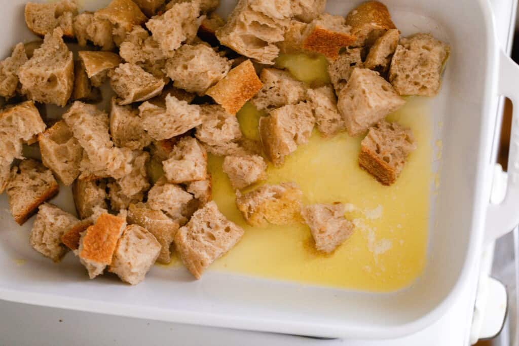 bread cubes tossed with butter in a white baking dish