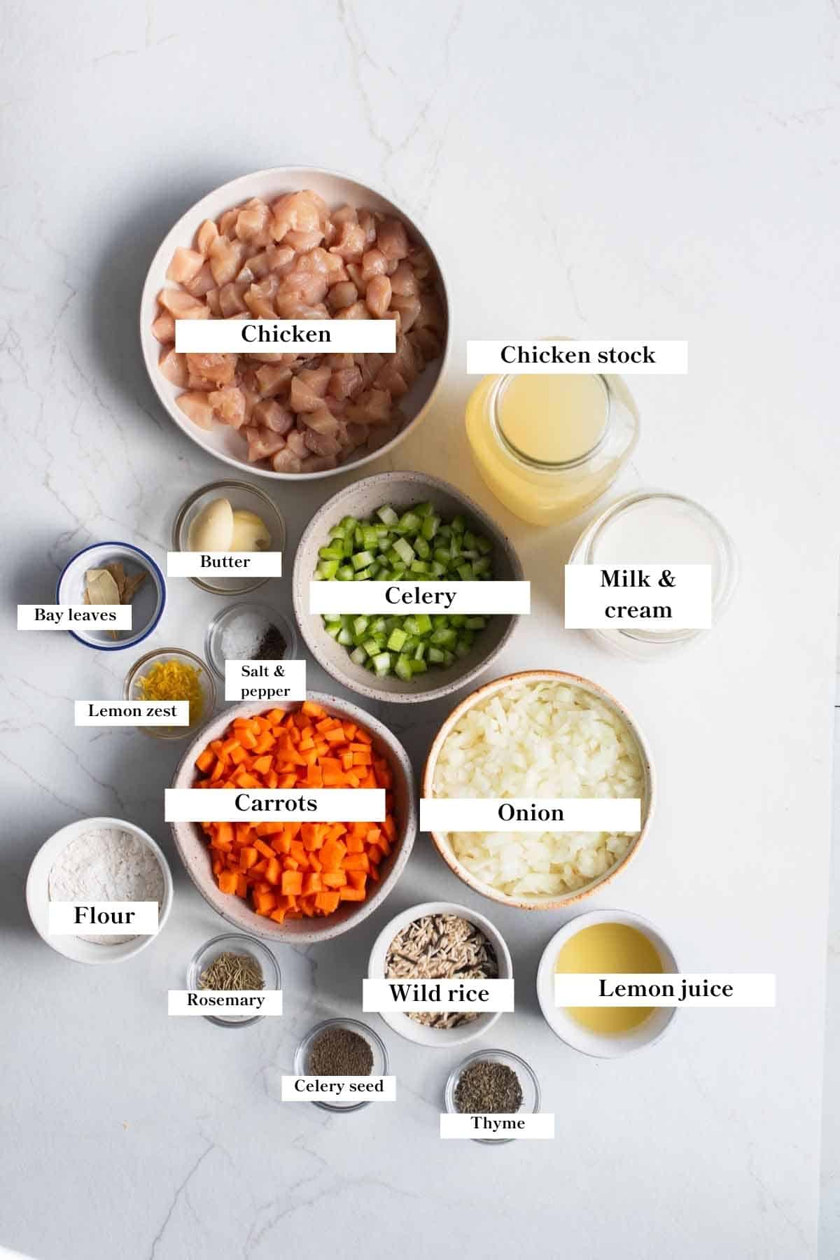 Ingredients for creamy chicken and wild rice soup in bowls and jars on a countertop.