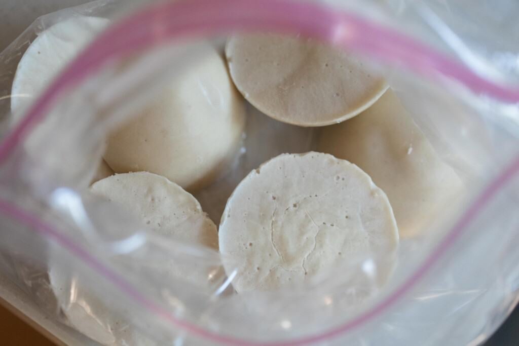 an open ziplock bag with frozen sourdough starter disks inside