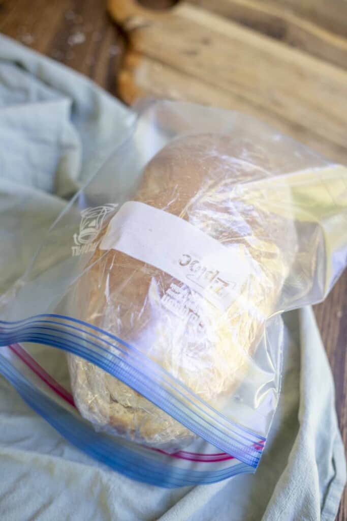 loaf of sourdough sandwich bread in a ziplock bag on a green towel