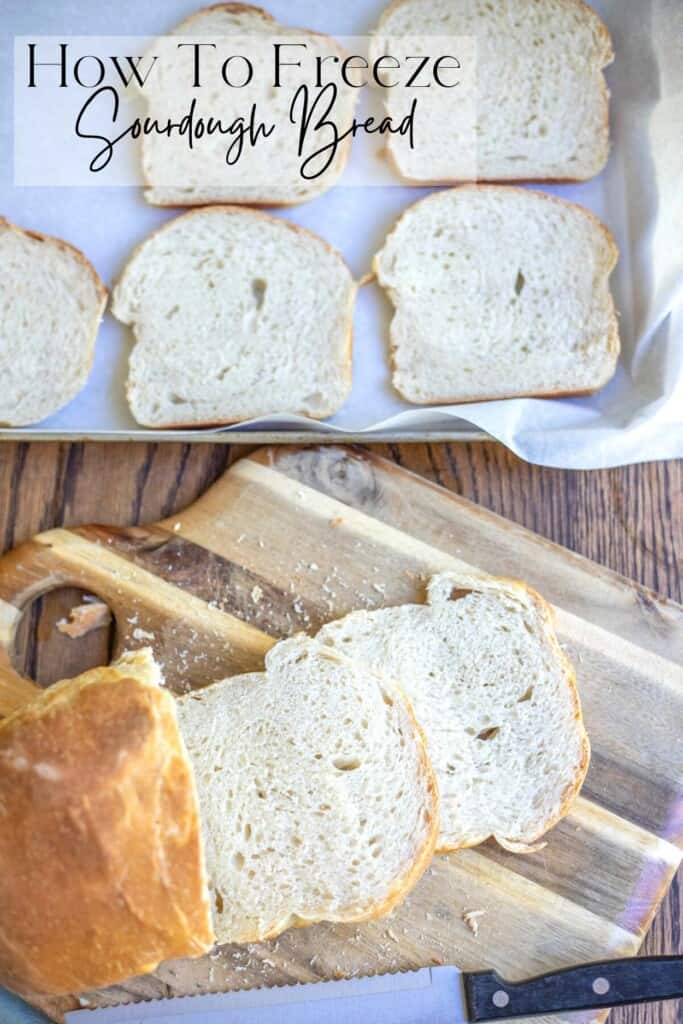 sourdough bread loaf cut on a cutting gbaord with a baking sheet of sliced bread in the background