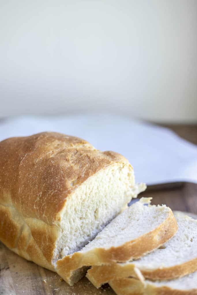 loaf of sourdough sandwich bread with pieces sliced off on a wood cutting board