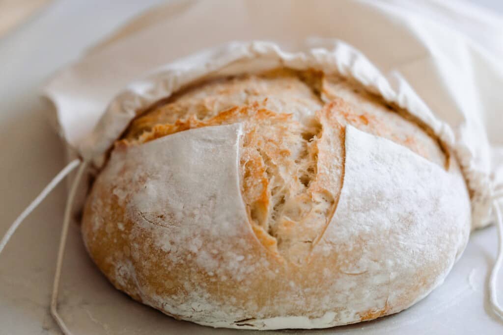 A sourdough loaf being placed in a linen bag