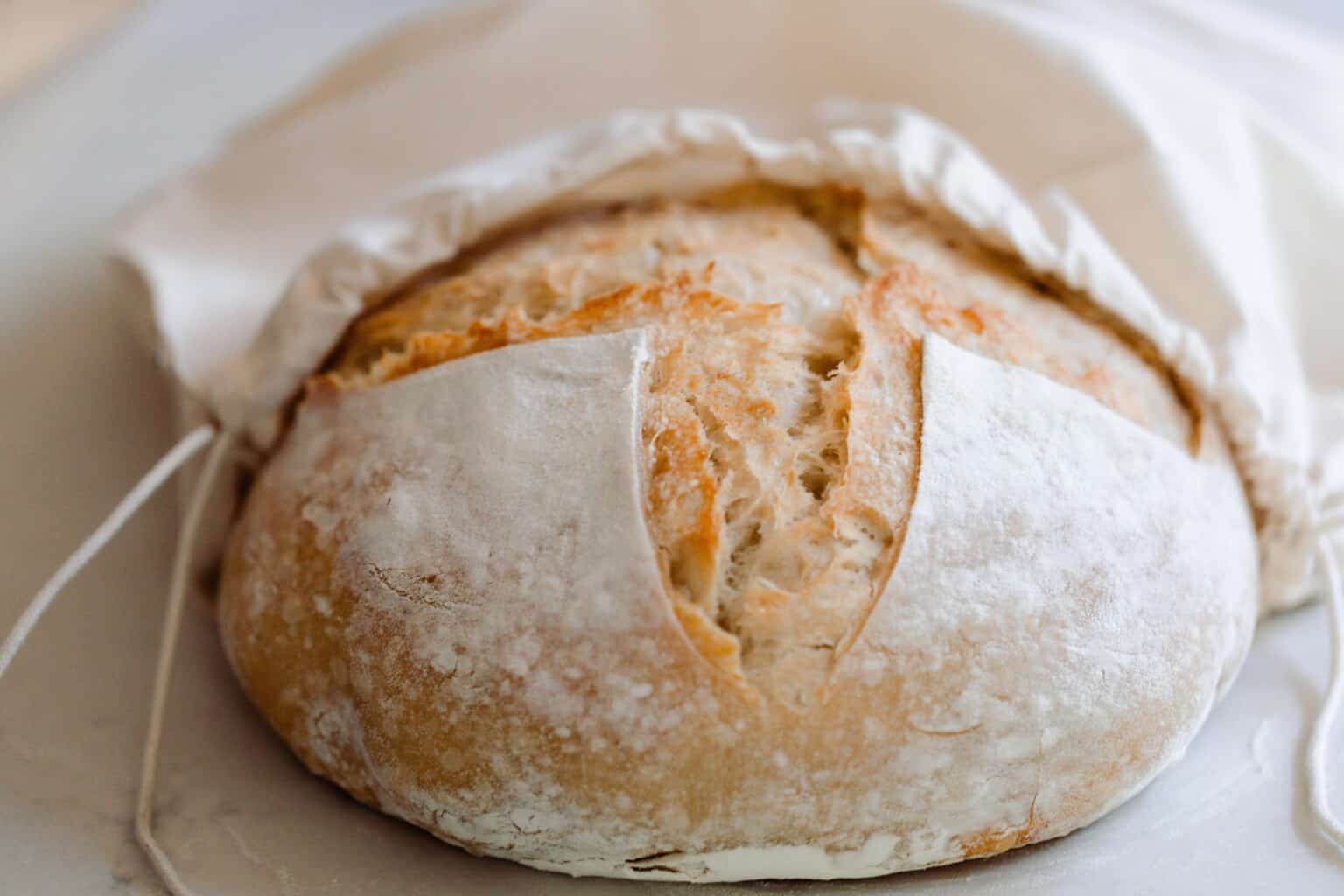 A sourdough loaf being placed in a linen bag