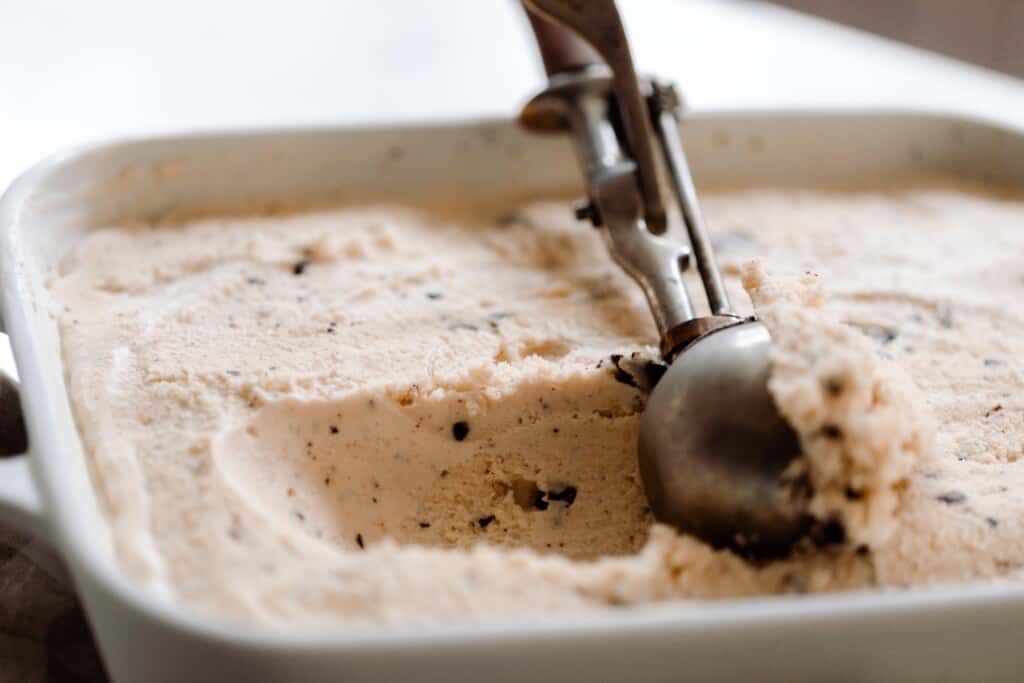 vintage ice cream scoop scooping out java chip ice cream in a white baking dish