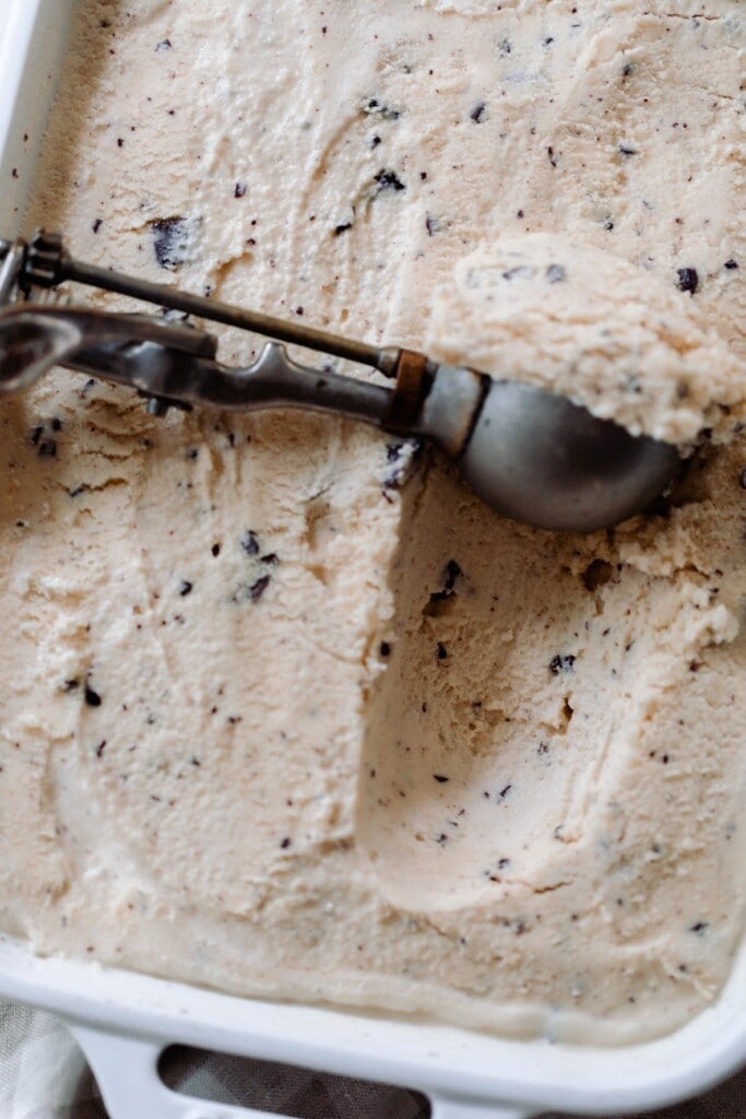 java chip ice cream in a baking dish with an ice cream scoop scooping out a scoop of ice cream