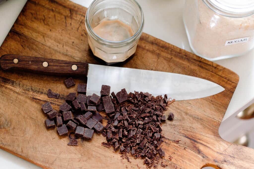 chocolate chinks chopped up on a wood cutting board with a knife sitting next to the chocolate