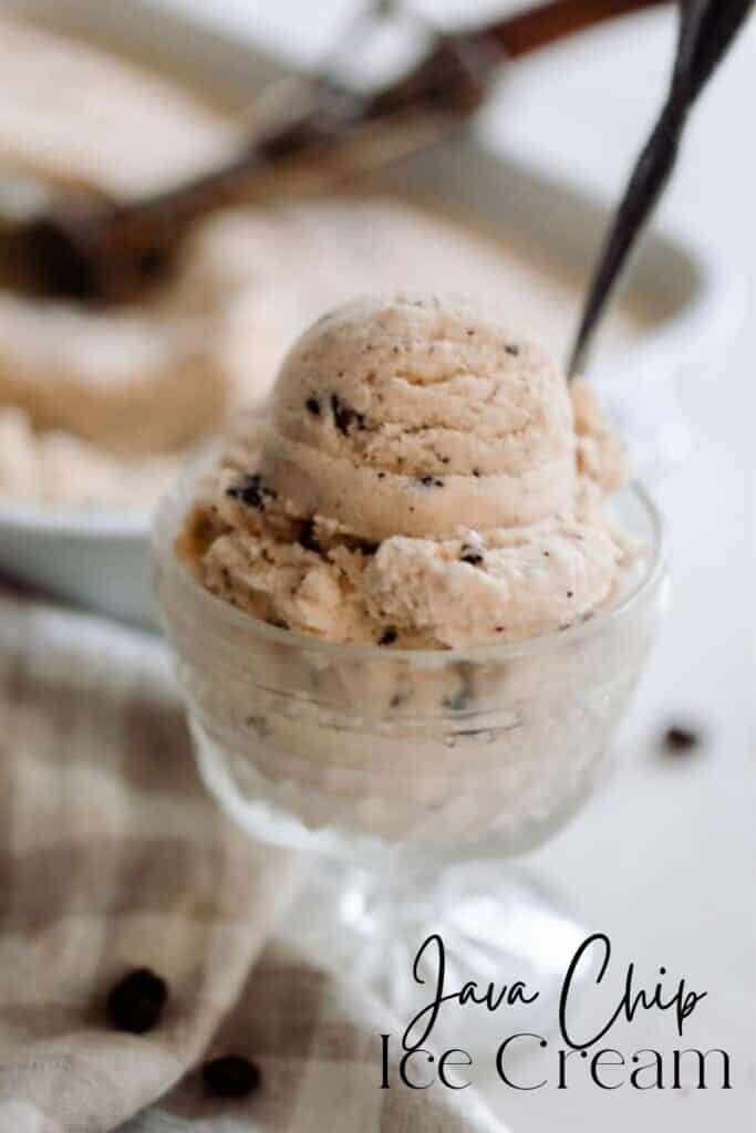 java chip ice cream scooped into a glass vintage ice cream dish with a spoon. The dish sits on a a white countertop op with a tan and white checked towel