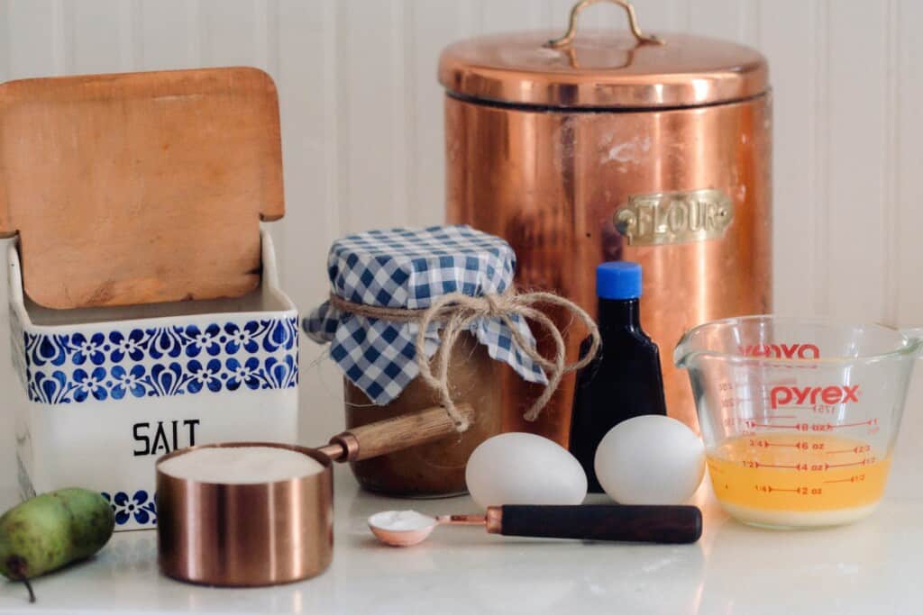 cannisters, jars, measuring cups, and eggs on a white countertop