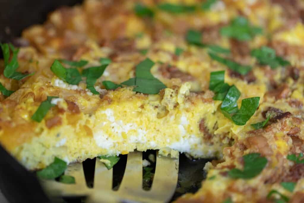 side view of a pumpkin frittata in a cast iron skillet with a slice taken out