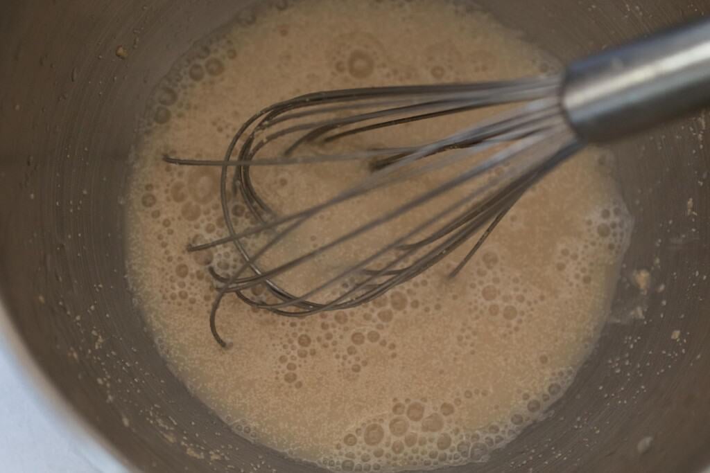 water, yeast and sugar in a stainless bowl with a whisk