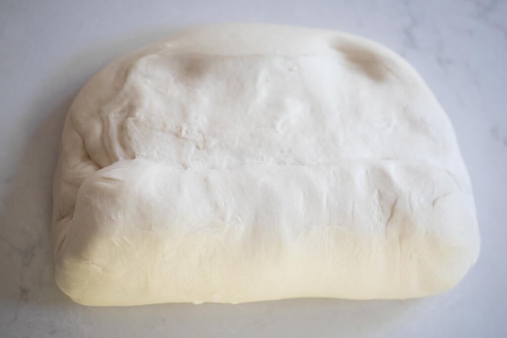 rolling up a loaf of bread on a white quartz countertop