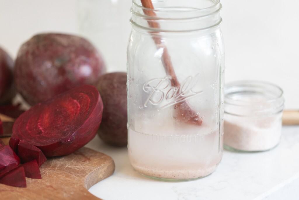 salt diluted in a jar with a wooden spoon. More salt and beets surround the jar