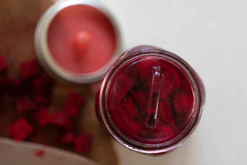 overhead photo of fermented beets in a jar with a silicon fermenting lid to the left