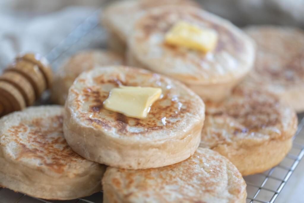 seven sourdough crumpets topped with butter on a platter 