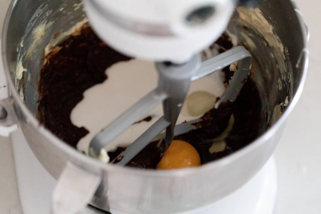 egg, sourdough starter and vanilla being added to creamed butter and sugar in a stand mixer bowl
