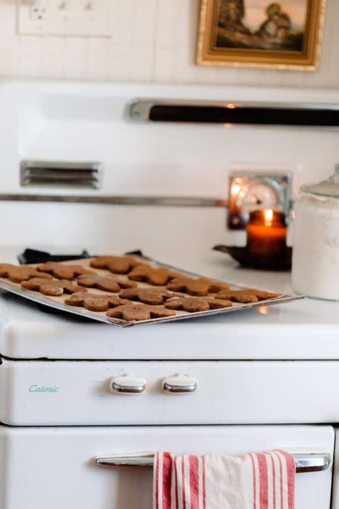 sourdough gingerbread cookies on a baking sheet on a vintage stove with a candle burning