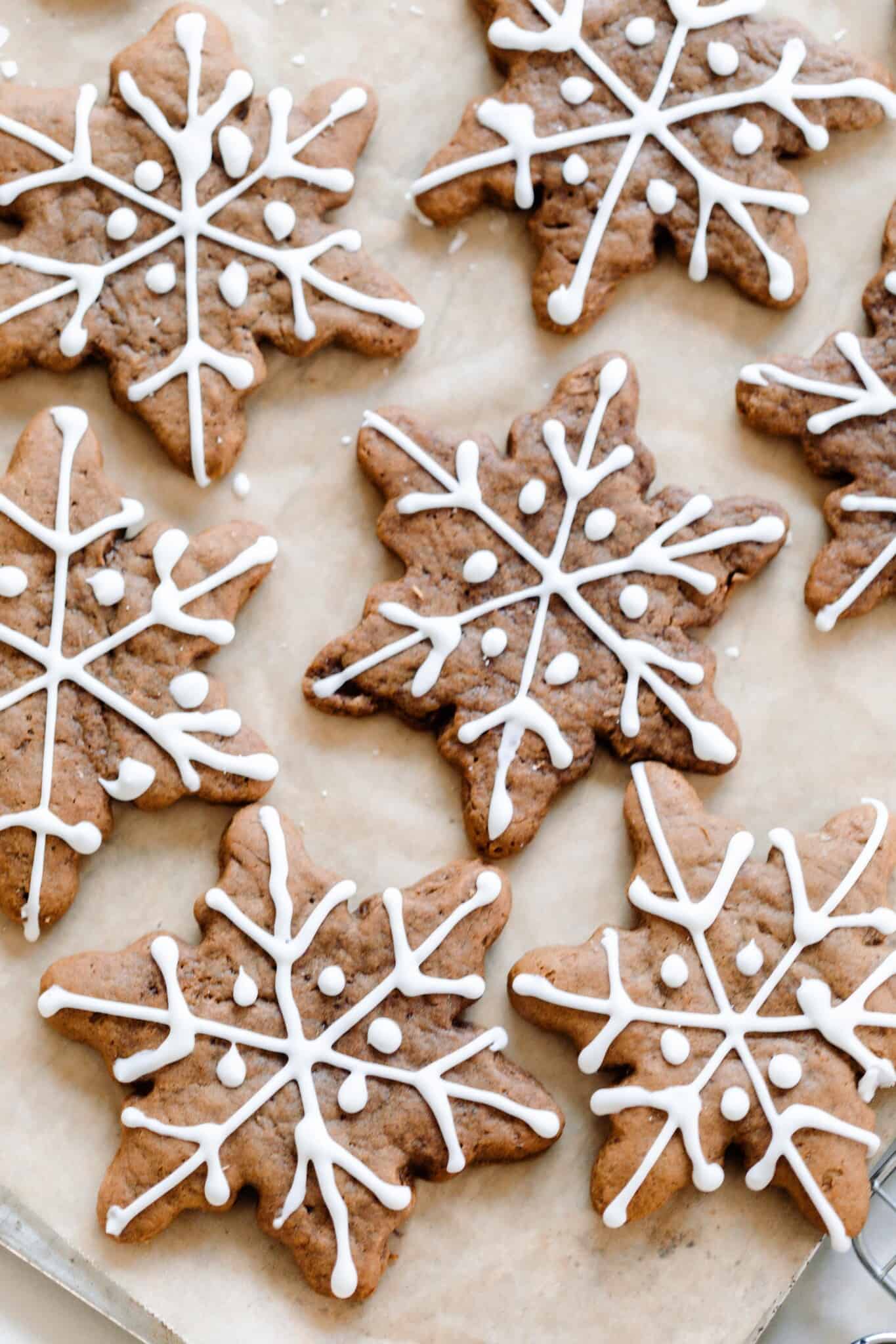 overhead photo of decorated sourdough gingerbread cookies in the shape of a snowflake  on parchment paper