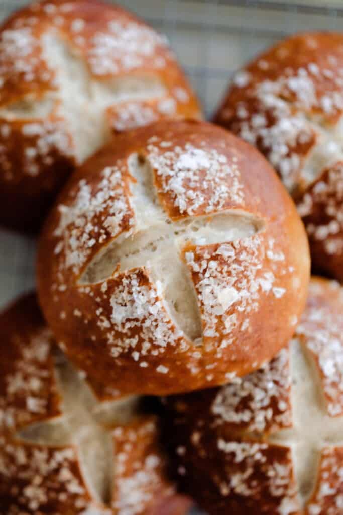 overhead photo of 5 sourdough pretzel rolls stacked in two layers on a towel