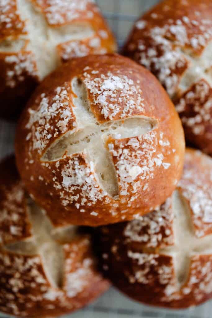 five sourdough pretzel rolls stacked in two layers