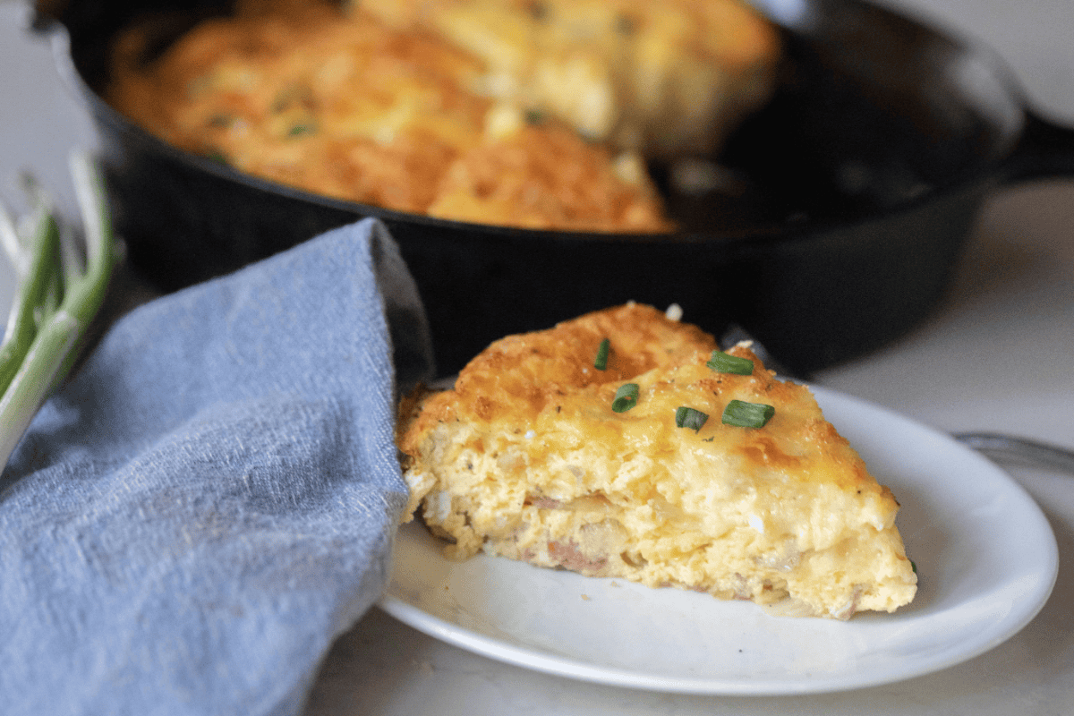A slice of ham and cheese frittata on a plate.
