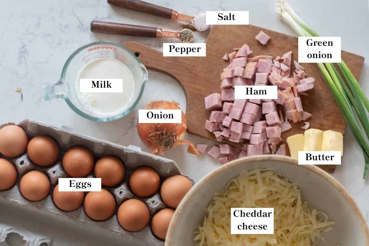 Ingredients for ham and cheese frittata laid out on a cutting board and countertop.