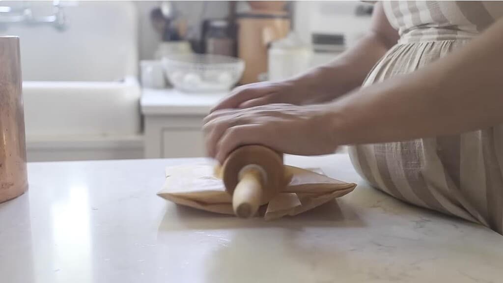 rolling out butter in parchment paper on a white countertop