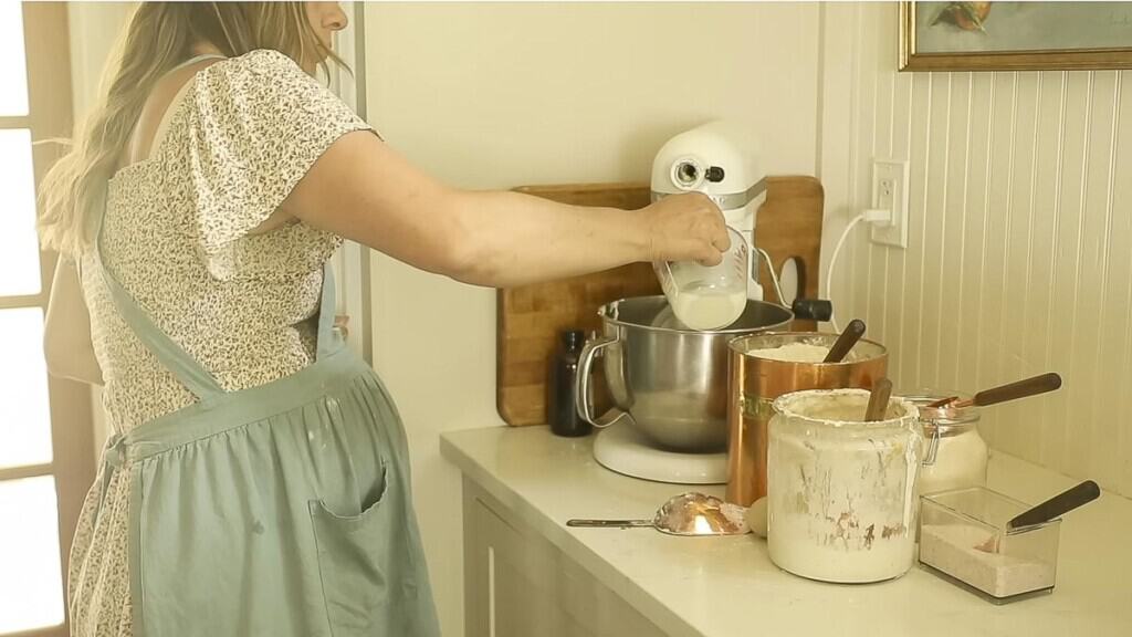 woman adding ingredients to a stand mixer in her kitchen