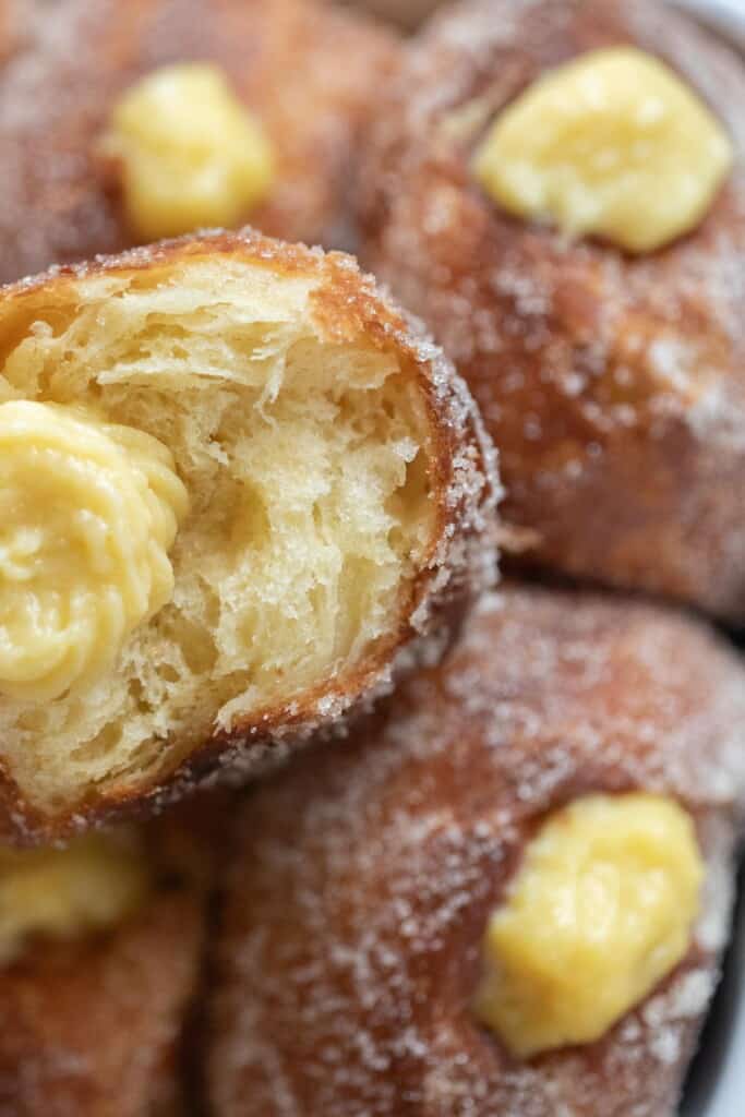 brioche donuts filled with a cream filling and tossed in sugar stacked on top of each other.