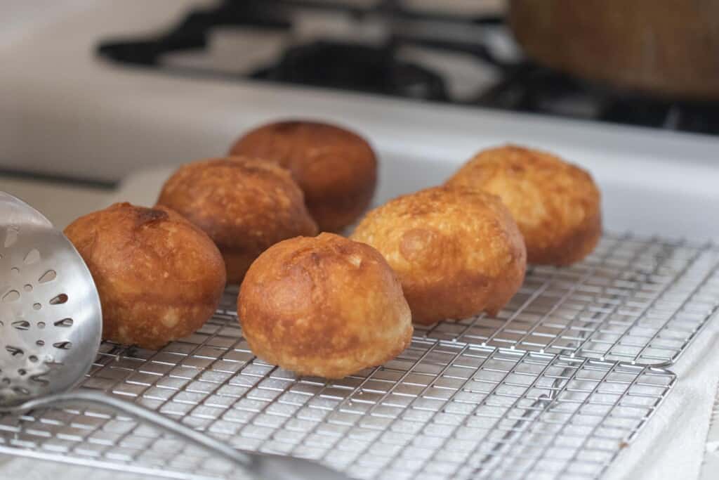 brioche donuts cooling on a wire rack next to a slotted spoon