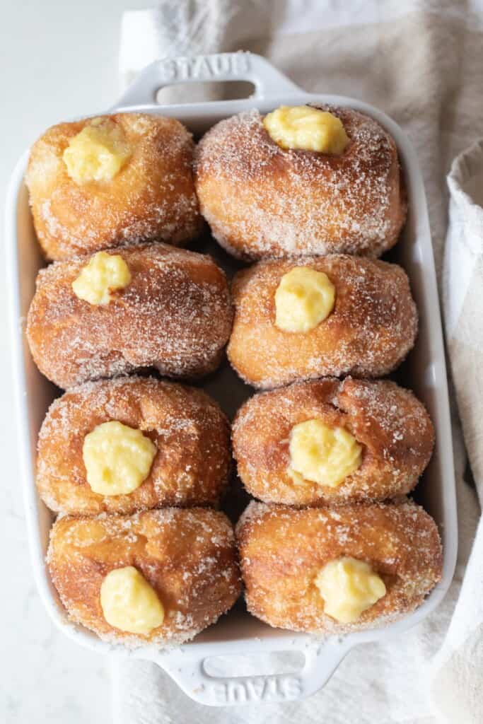 Brioche donuts filled with custard in a gray pan on a white counter top